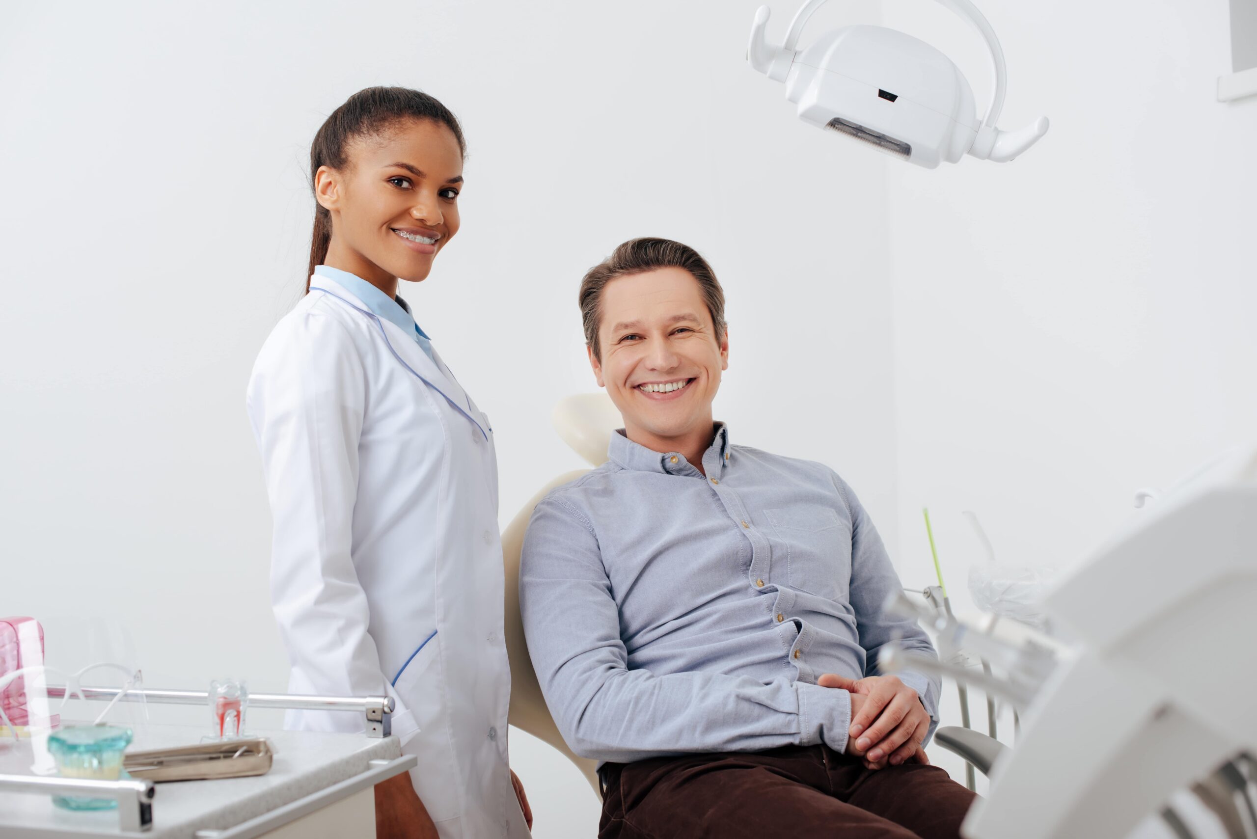 Selective focus of happy patient smiling with cheerful african american dentist in braces
